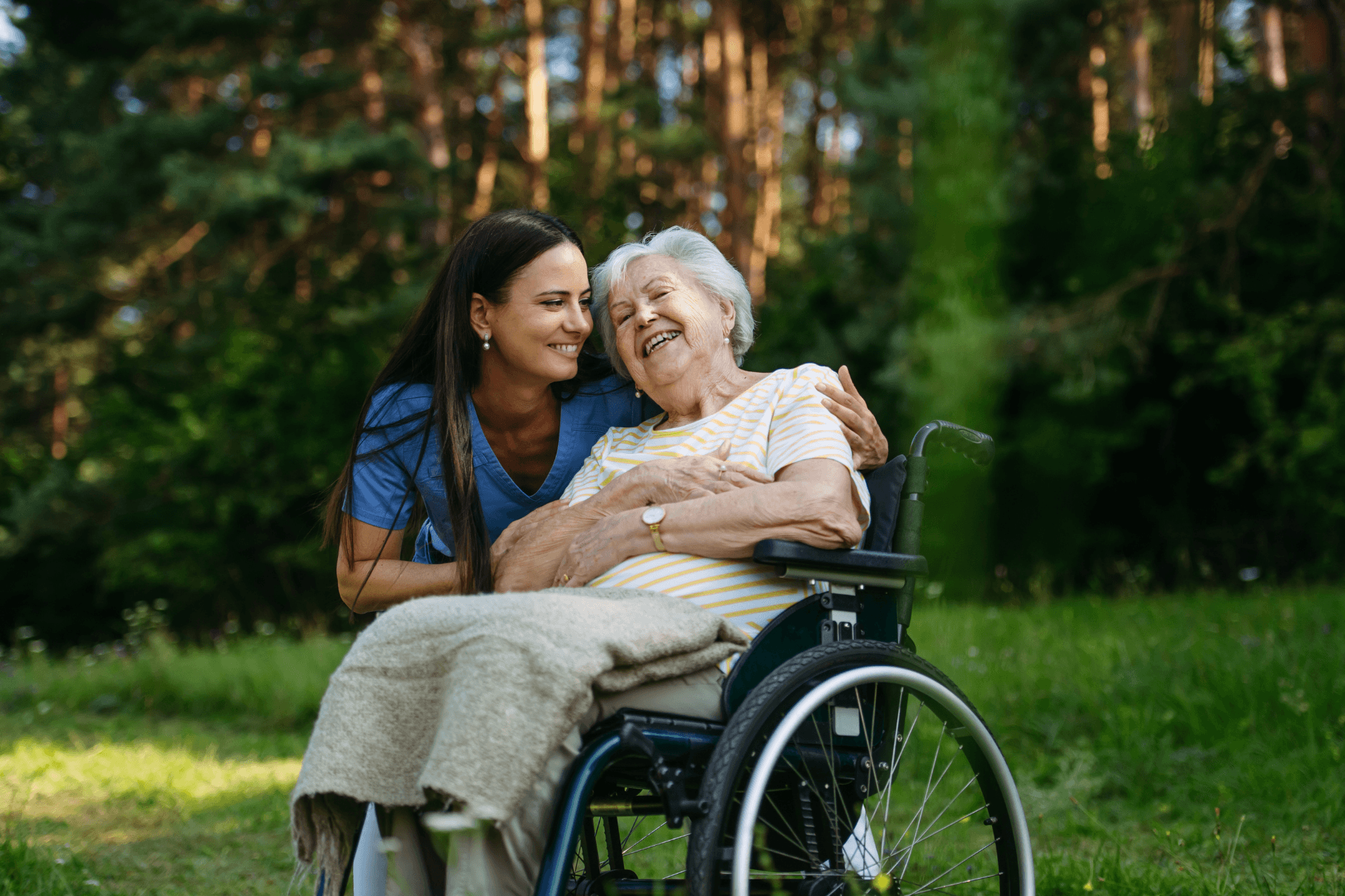 A caring caregiver embracing an elderly woman in a wheelchair outdoors