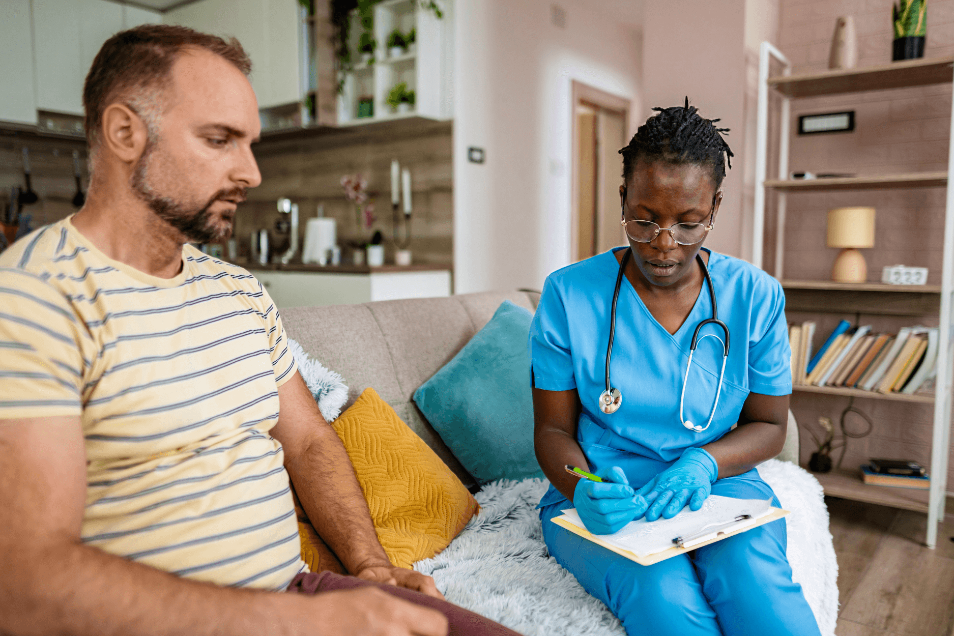A nurse consulting with a patient at home, reviewing care notes together